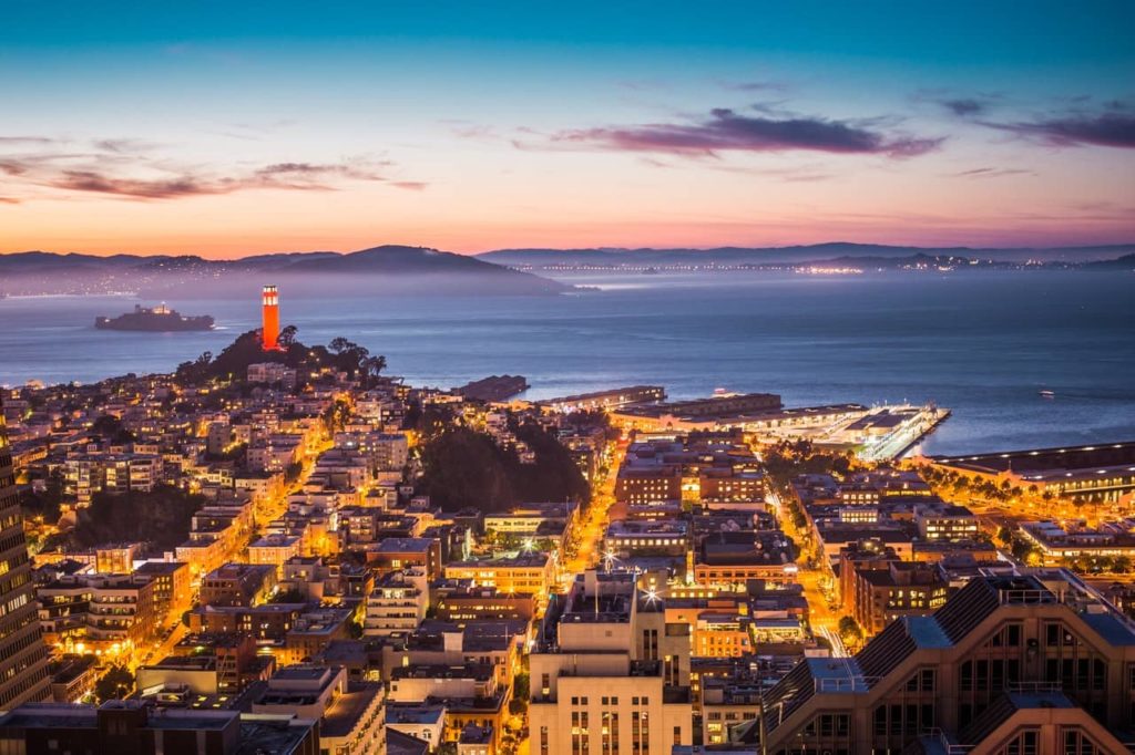 A zoomed out aerial view of San Francisco real estate at dusk, illustrating the idea of seeing the full picture when you trade up or upgrade homes in a down or buyer's market.