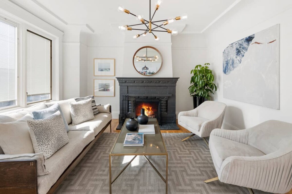 We helped to sell this Glen Park home, pictured in the professionally staged living room with a couch and chairs, white walls, a dark-painted fireplace, and contemporary light fixtures.