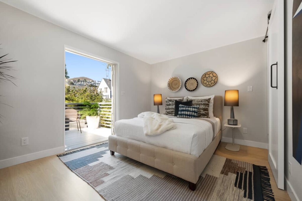 Bedroom with open doors to a private balcony and sunlight, in a home in Noe Valley sold by Danielle Lazier Vivre Real Estate Agents San Francisco.