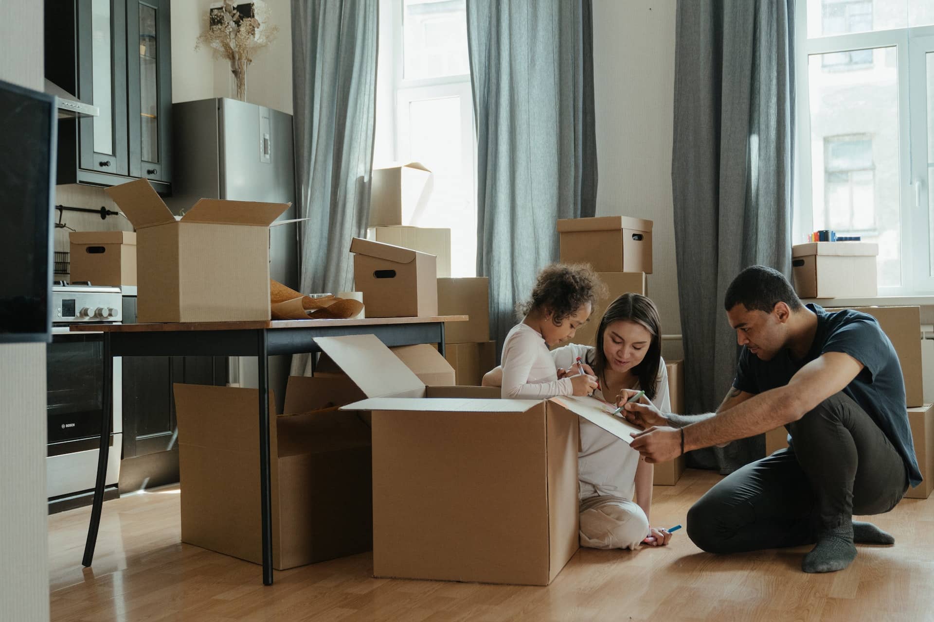 A family packs boxes for their upcoming move, symbolizing sell San Francisco home without moving staging.
