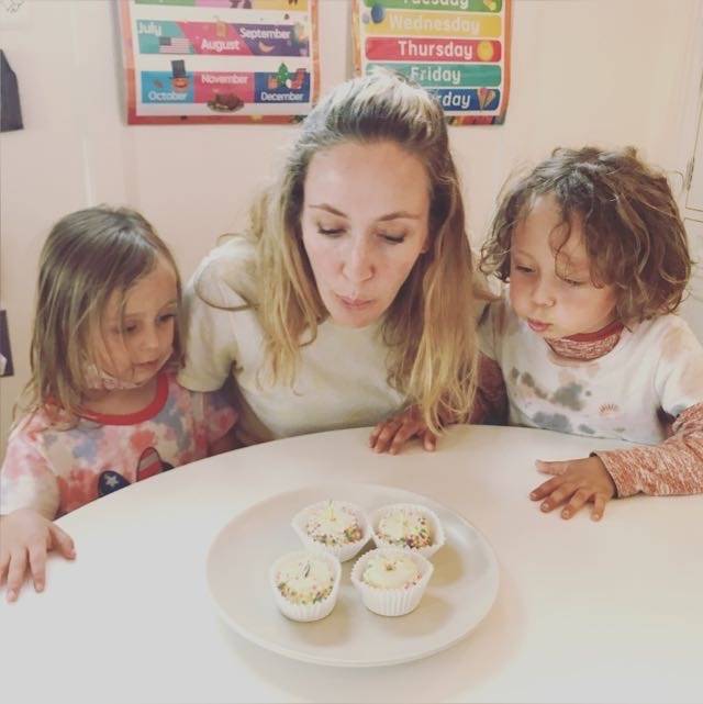 Danielle at a table with her twins, blowing out candles on birthday cupcakes.