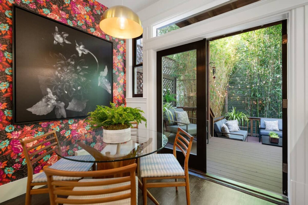Cozy eat-in dining area in Soma condo with stylish wallpaper and French doors opening to a quaint backyard.