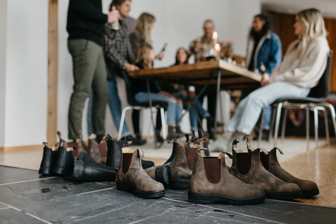 Stylish Boots Offered for Sale from Footprint Shoes & Clothing Store with Group of People Sitting at Table in Background
