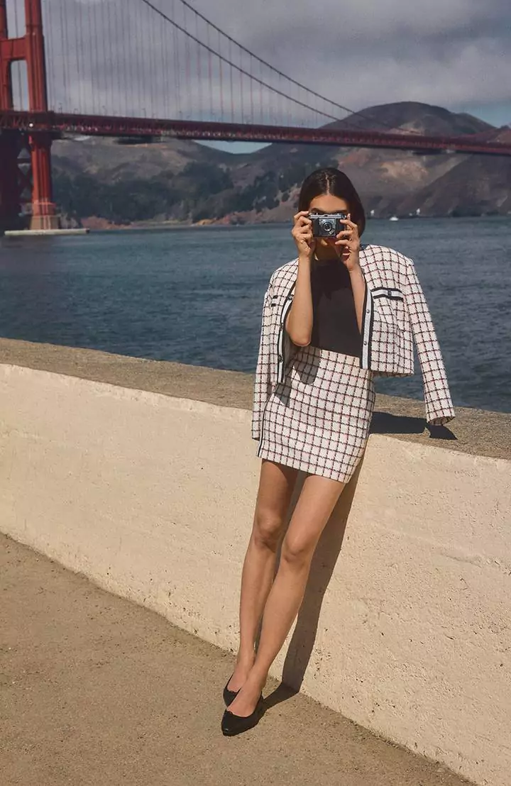 Woman Dressed in Veronica Beard Matching Mini Tweed Skirt and Jacket While Taking a Photo with the Golden Gate Bridge in the Background
