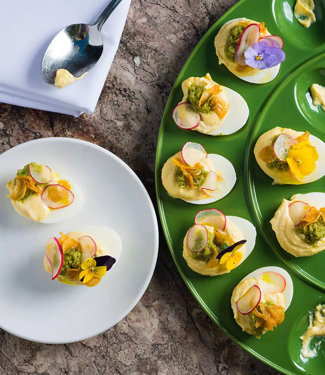 Fancy Deviled Eggs Appetizer topped with Green Sauce, Thinly Sliced Radishes, and Edible Flowers from Blue Plate San Francisco
