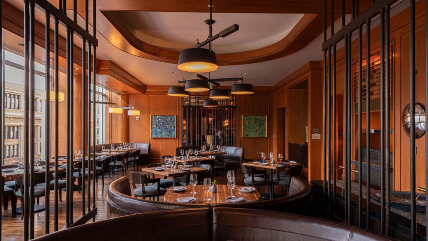 View of Upscale Dining Room with Tables Set and Waiting for Diners, Rich Wood-Paneled Walls, Contemporary Lighting, and Floor-to-Ceiling Views of Downtown