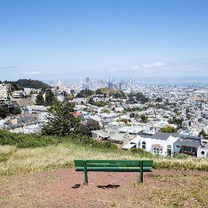 Green park bench atop Tank Hill with panoramic skyline views of San Francisco