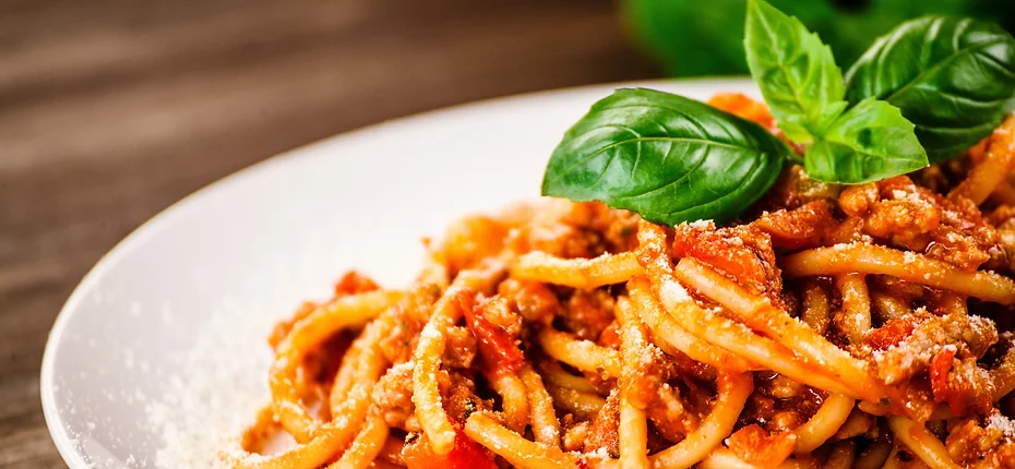 Close up Of Spaghetti with Red Meat Sauce, Topped with Grated Parmesan Cheese and Fresh Basil