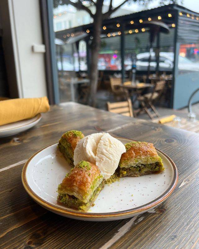 Dish of Baklava with Ground Pistachio and Vanilla Ice Cream served on an outdoor table at Lokma