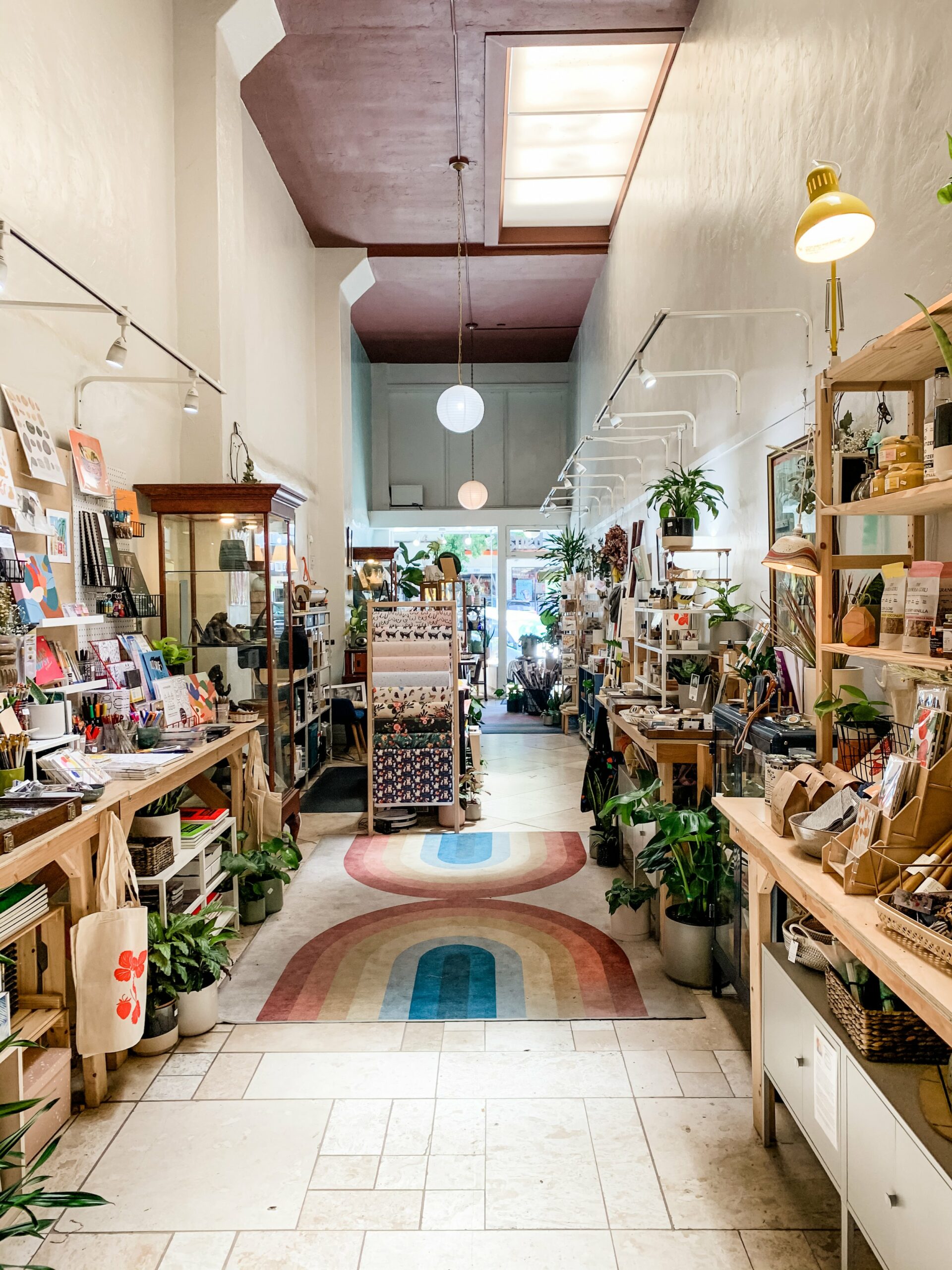 Interior of Bay Made shop with a wide array of unique and local goods on display for sale including cards, notebooks, packaged food and drink products, plants, candles, and more