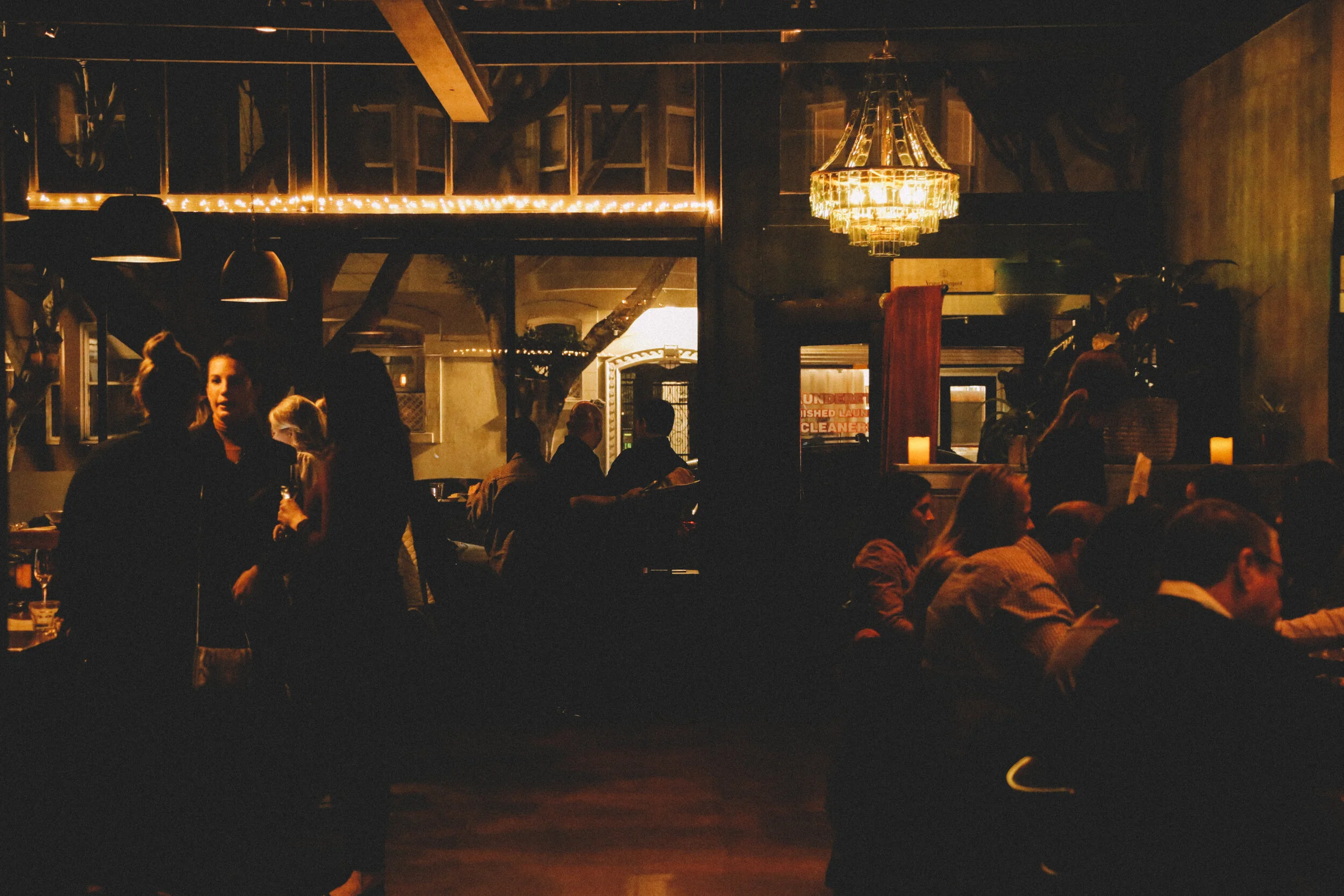 Darkly lit upscale dining room packed full with diners and waitstaff at Seven Hills restaurant in Russian Hill