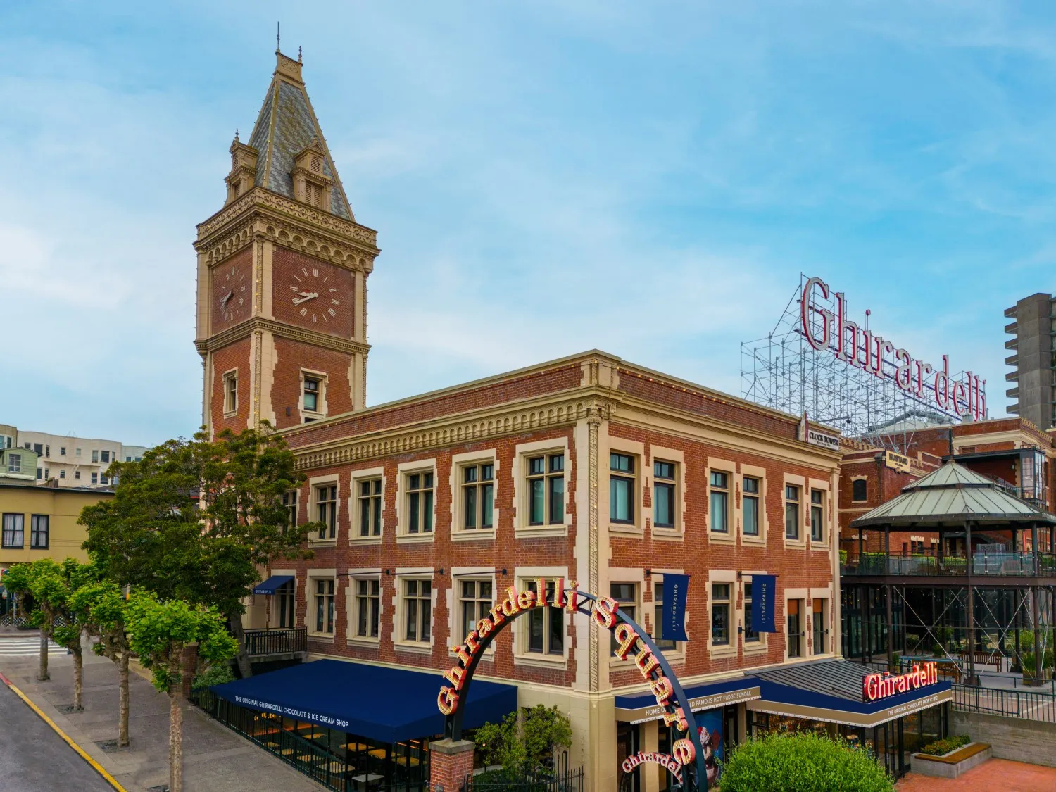 Exterior of brick building with high clock tower with large entry sign that states Ghirardelli Square outside