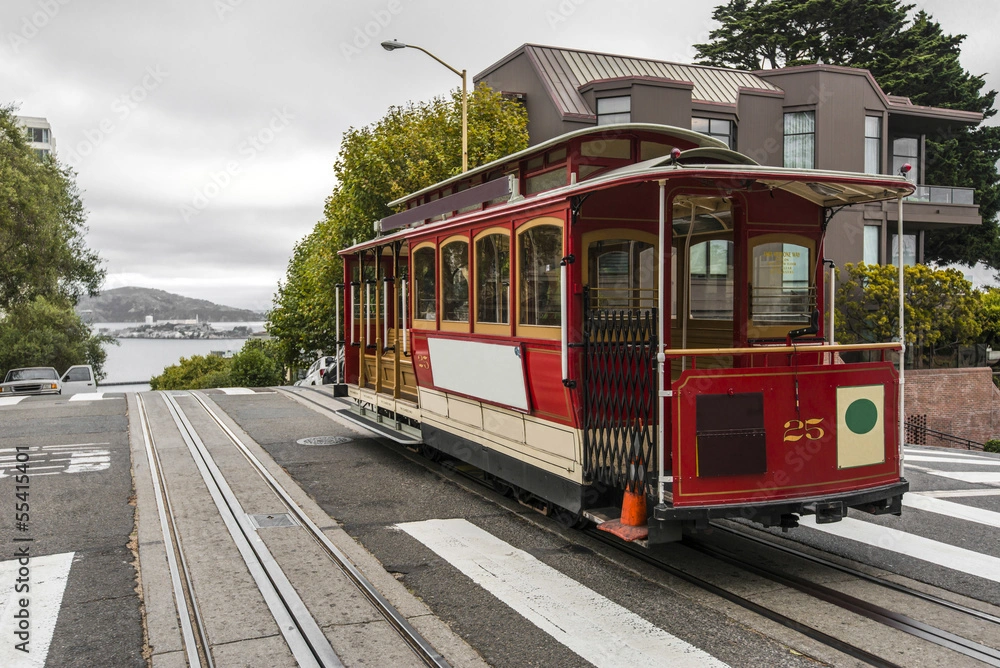 One of the famous San Francisco cable cars in downtown SF with the bay in the background