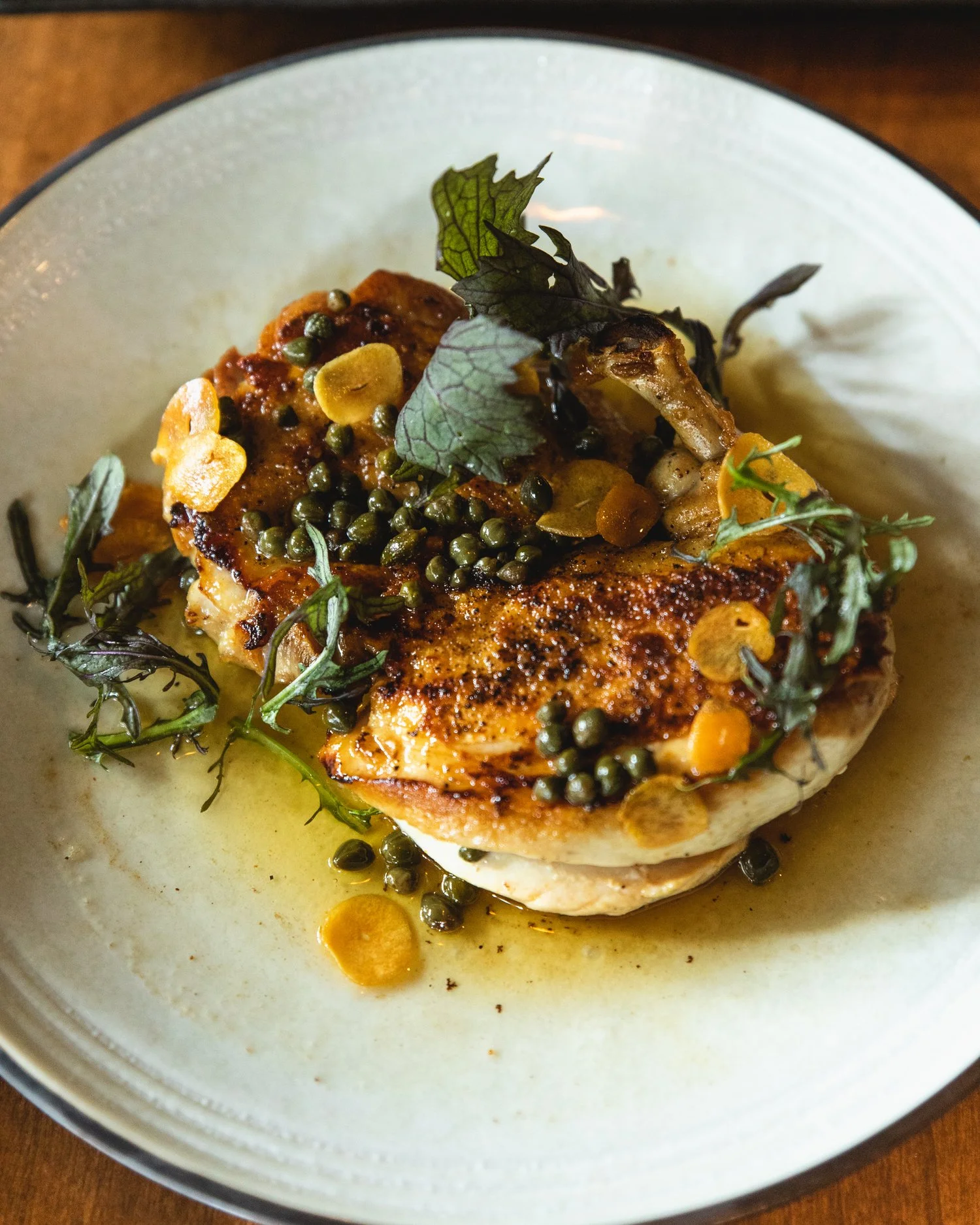 Pan Seared Fish topped with thinly sliced carrots, greens, and capers