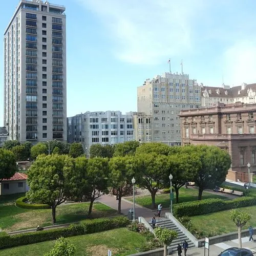 Tree lined green space and staircase walkway at Huntington Park, surrounded by skyrise and midrise buildings in San Francisco