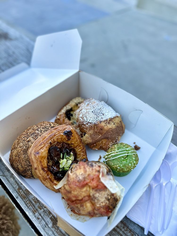 Box with six baked goods and pastries including multiple danishes, a muffin, and croissant from Neighbor Bakehouse