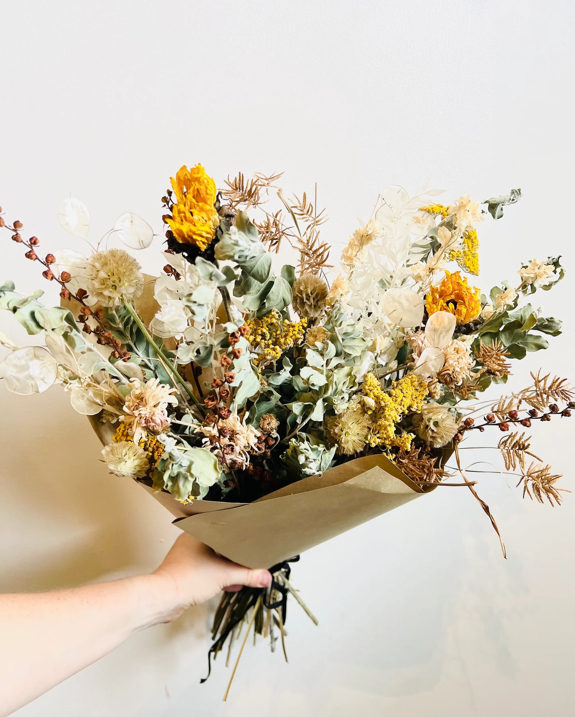 Hand holding a large dried bouquet arrangement from Revel Shop in the Dogpatch